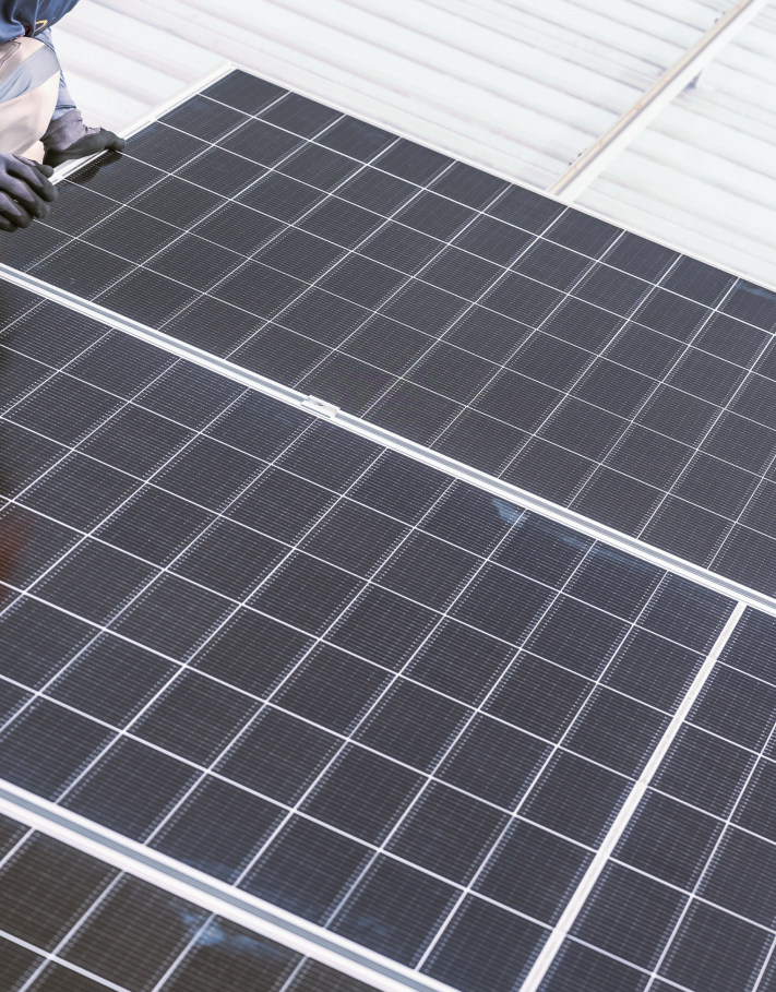 Close-up of a technician installing a home solar power system on a metal roof