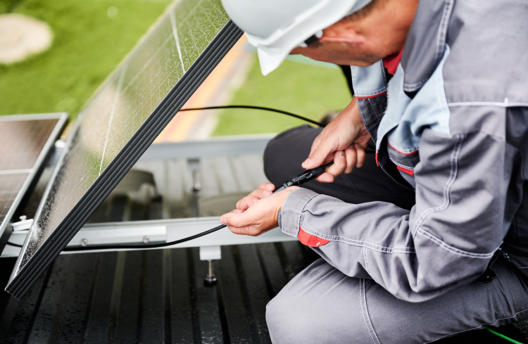 Technician connecting cables during PV panel installation