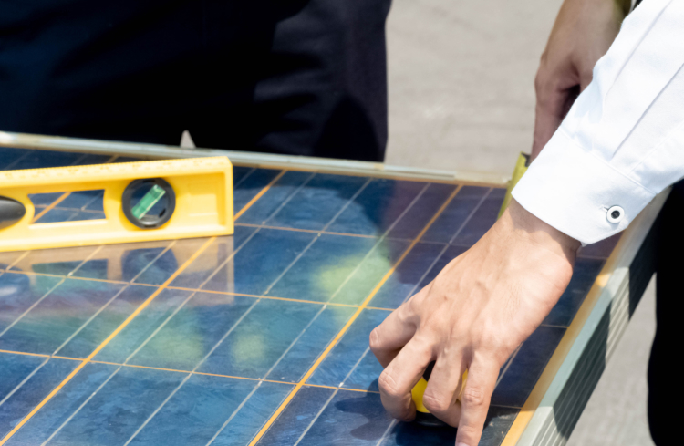 Technician checking solar panel alignment during installation with a level.